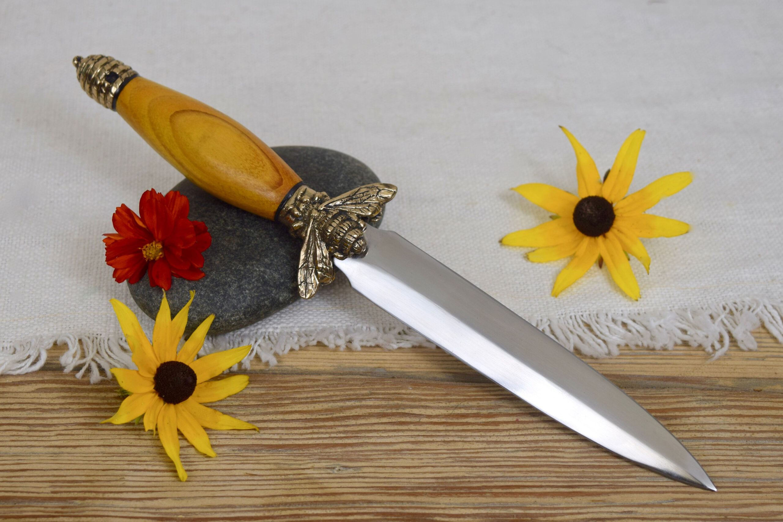 A double edged knife with a bee design
